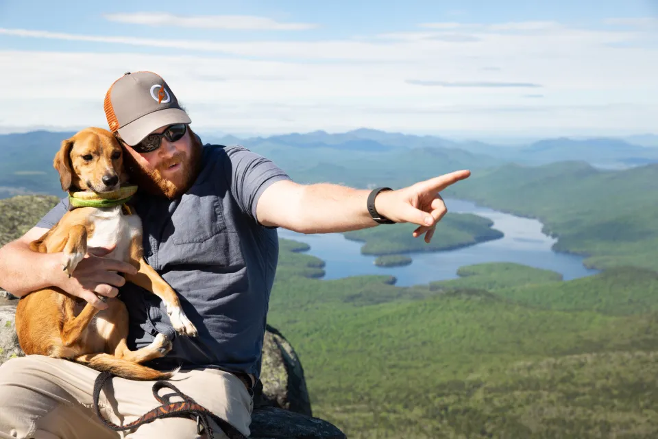 Man on the top of a mountain holding his dog