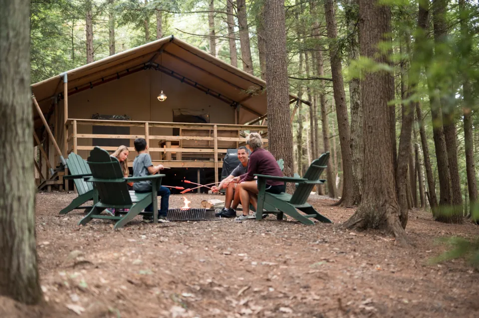 A family in front of a glamping cabin roasting marshmallows