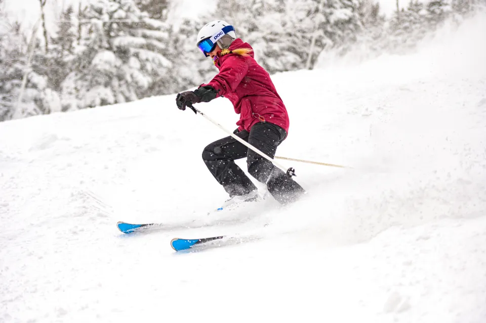 A man in a red jacket skis down a mountain. 