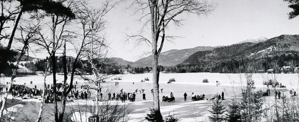 A vintage black and white photograph of sports taking place on a frozen lake.