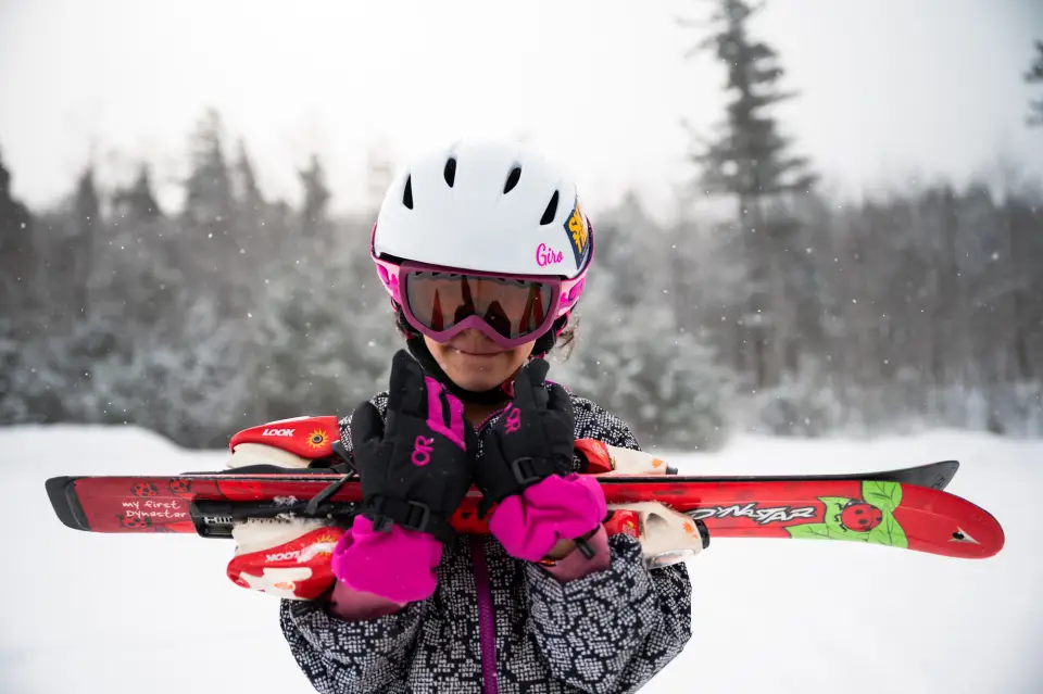 A girl carries some skis