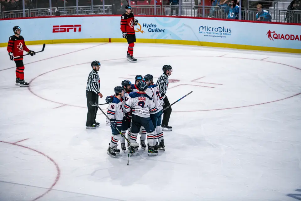 A team of hockey players cluster together in celebration on the ice.