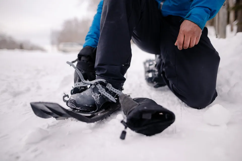 A person strapping on snowshoes