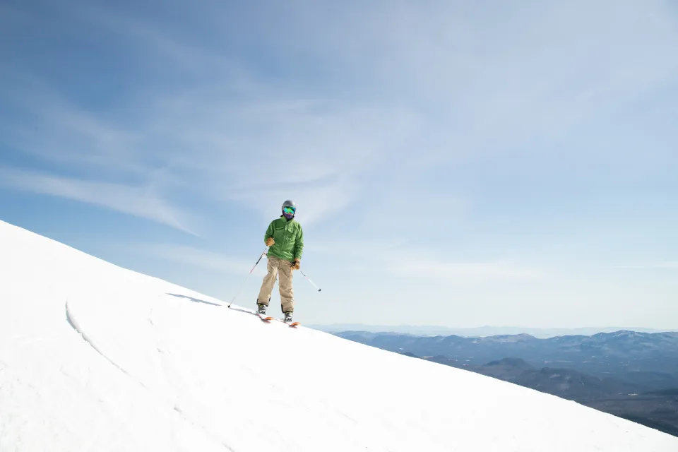 A skier standing on the side of a snowy mountain.