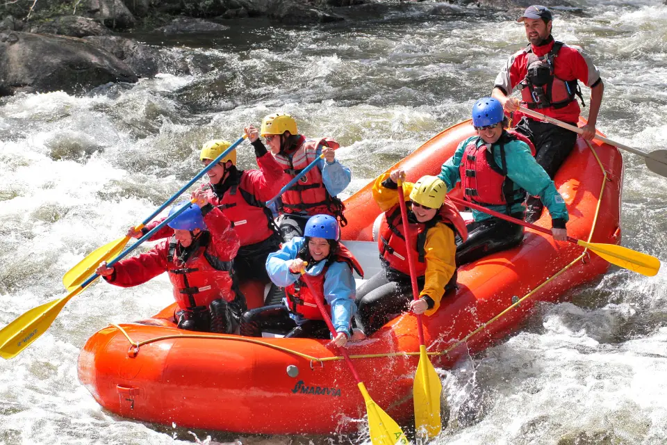 A raft of people paddle down rapids.