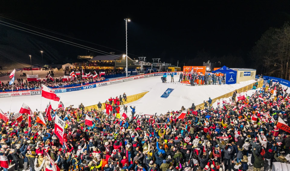 A crowd of spectators watching athletes at the ski jumps.