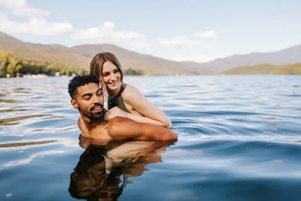 A man and woman go swimming in a lake.