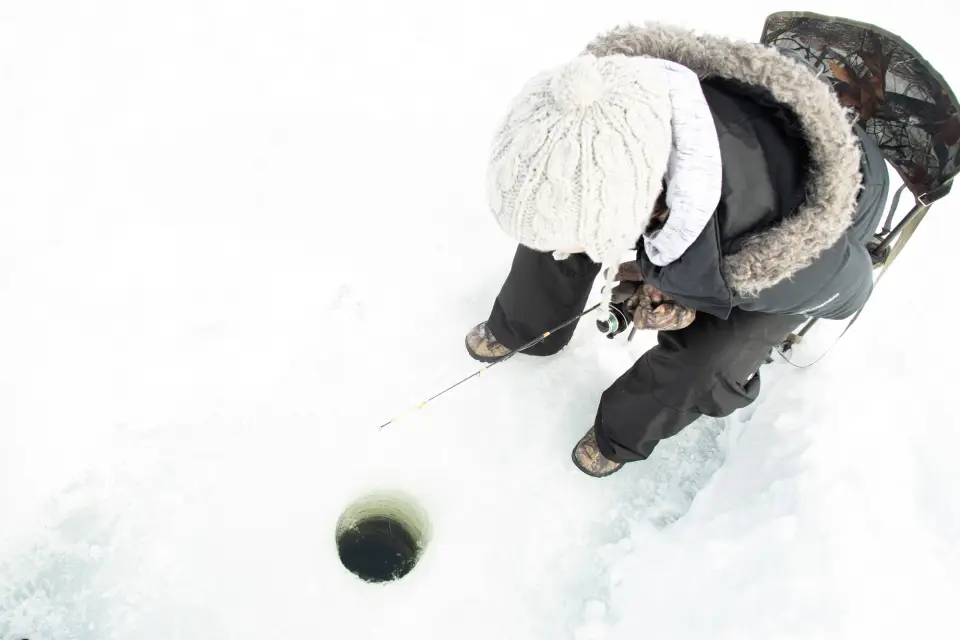 An ice fisher next to a hole