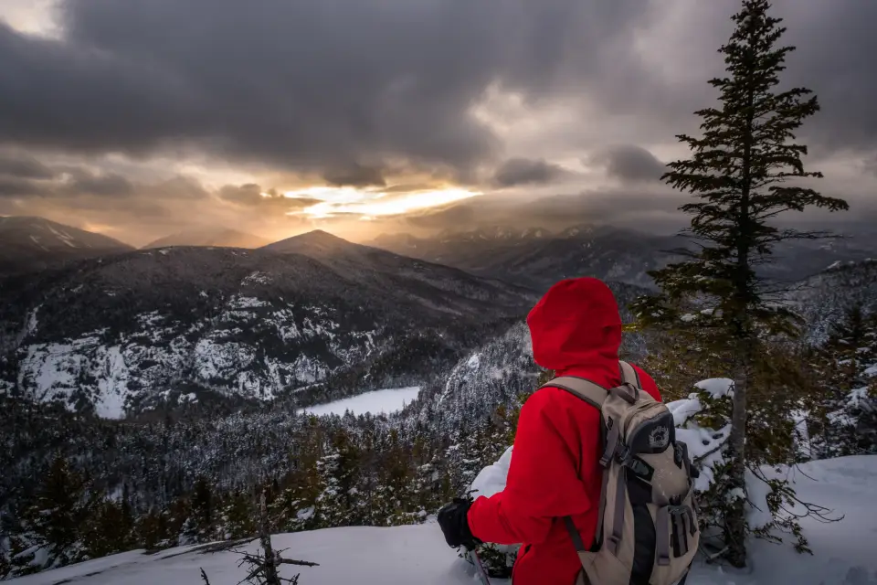 A hiker looking out at winter summit views on a hike.