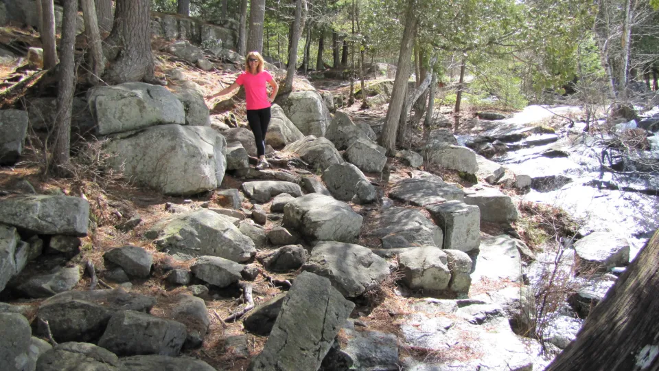 A woman standing next to a flowing river while on a spring walk.