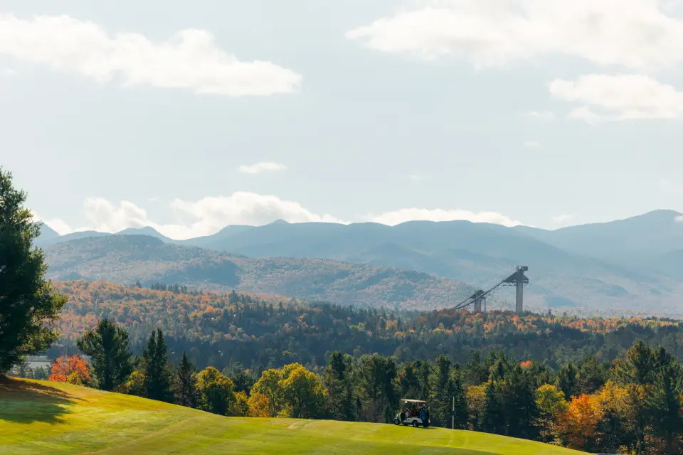 Green golf courses with fall foliage and the Olympic Ski Jumps in the backgrounds.