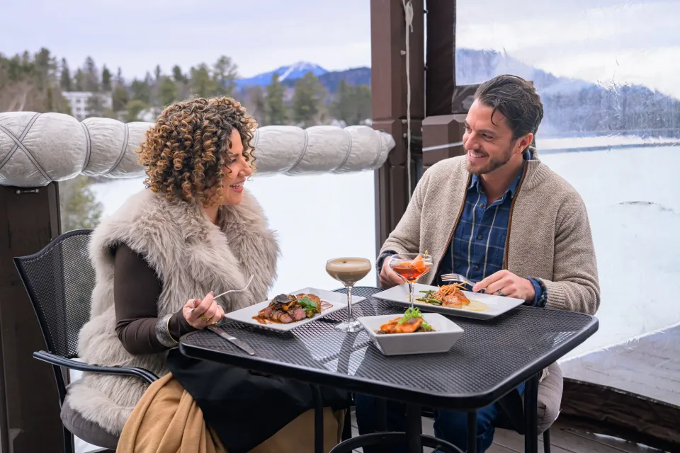 Two people dining on an outdoor patio during the winter in Lake Placid.