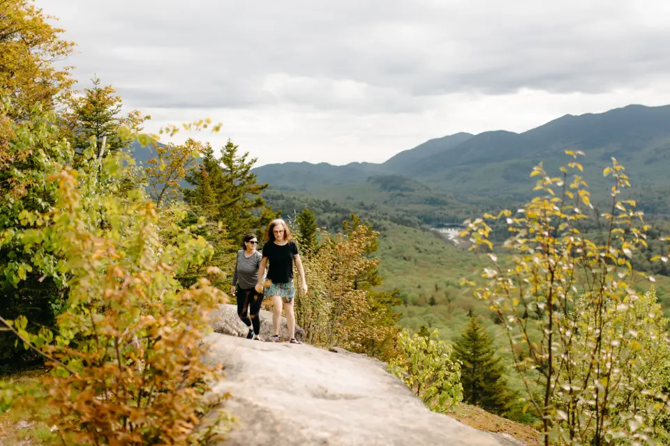 Two women hiking on a forested peak.