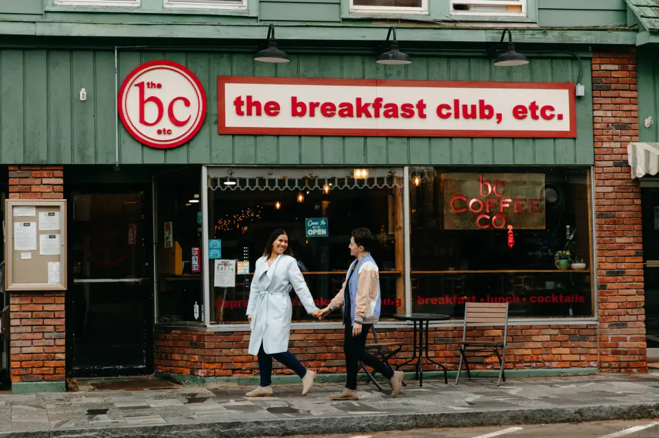 A couple walking down Main Street in front of the Breakfast Club restaurant.