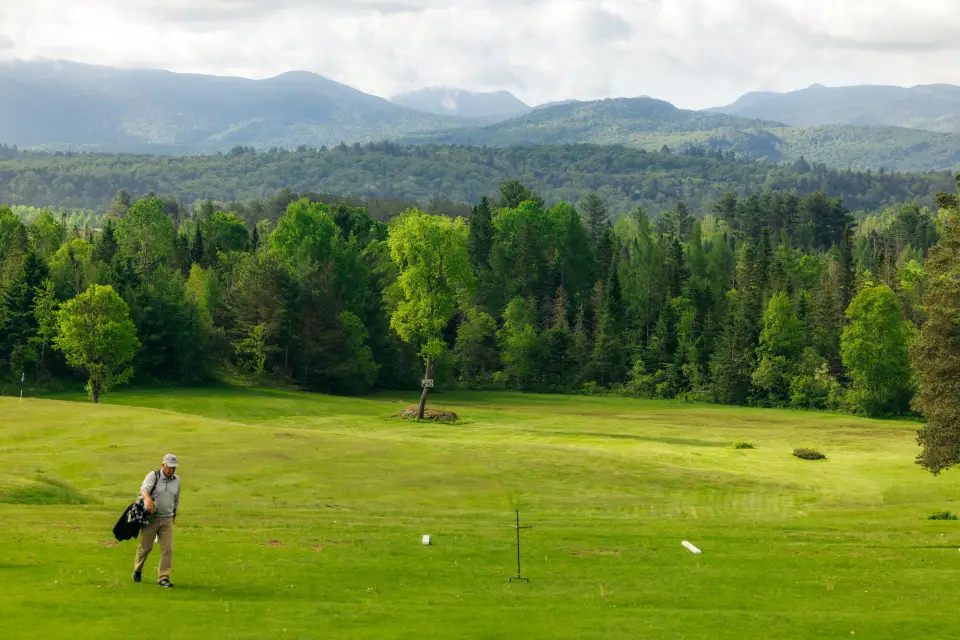 A golfer walking across a Lake Placid golf course