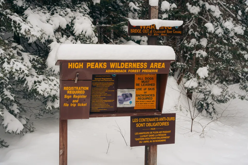 A High Peaks Wilderness hiking trailhead in a snowy forest.