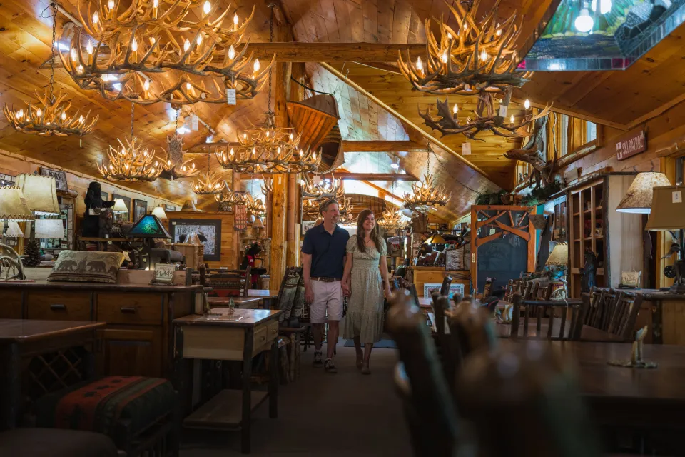 A man and woman explore a rustic luxury furniture store adorned with twinkling lights.