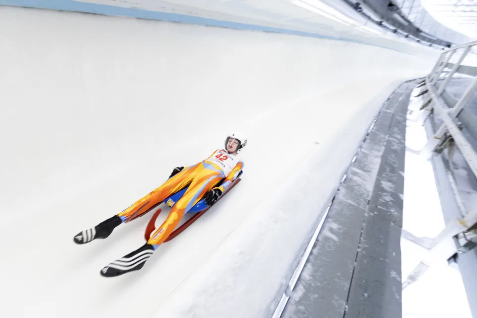 an olympian races down an icy track. 