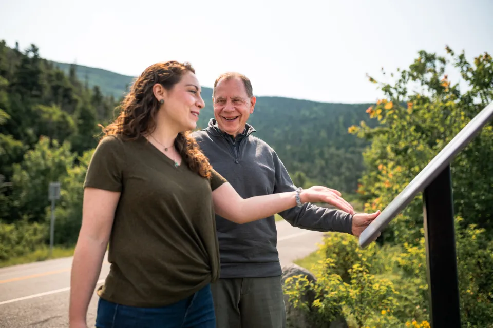 A man and woman read over a path sign with information. 